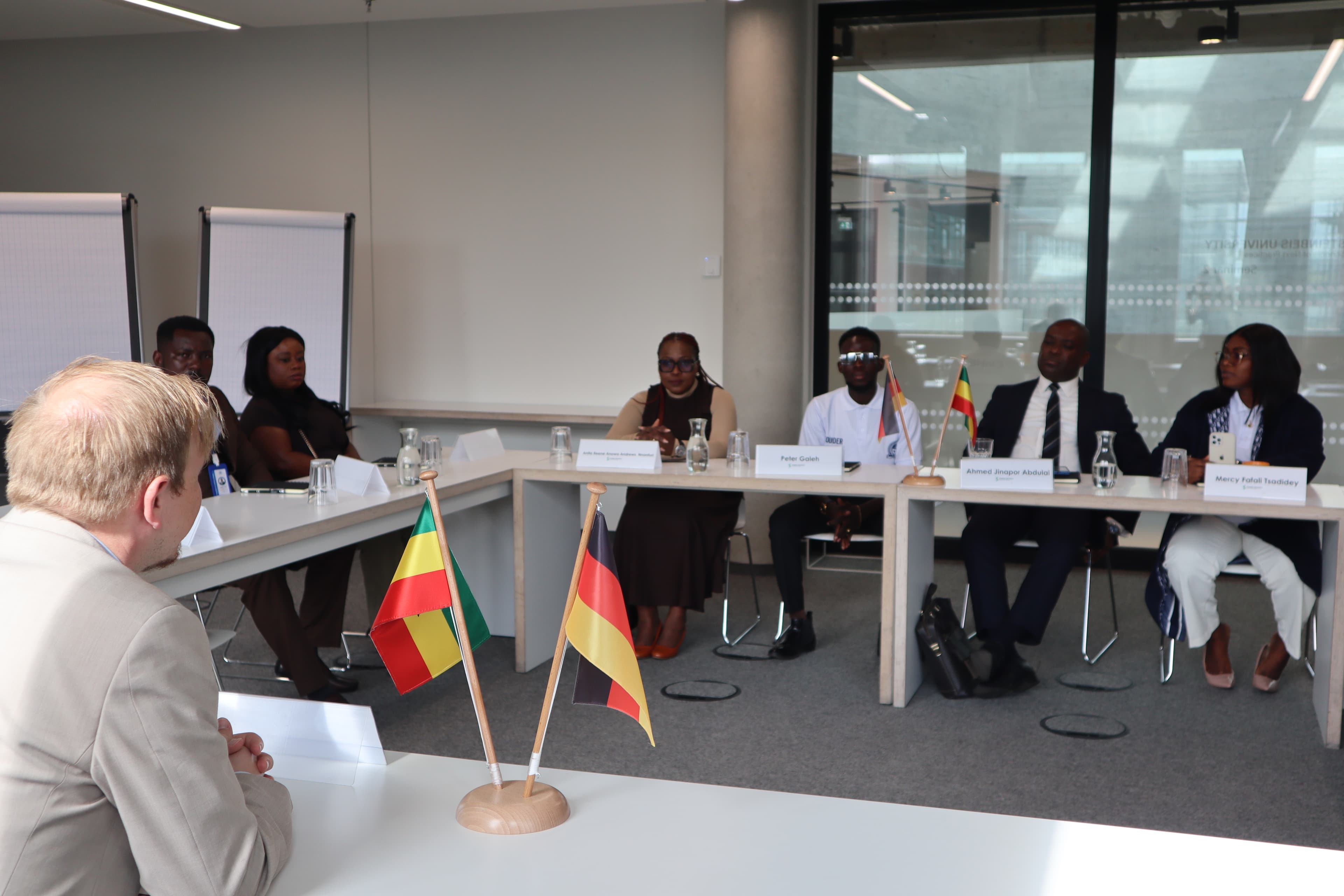 Participants seated around a U-shaped meeting table.