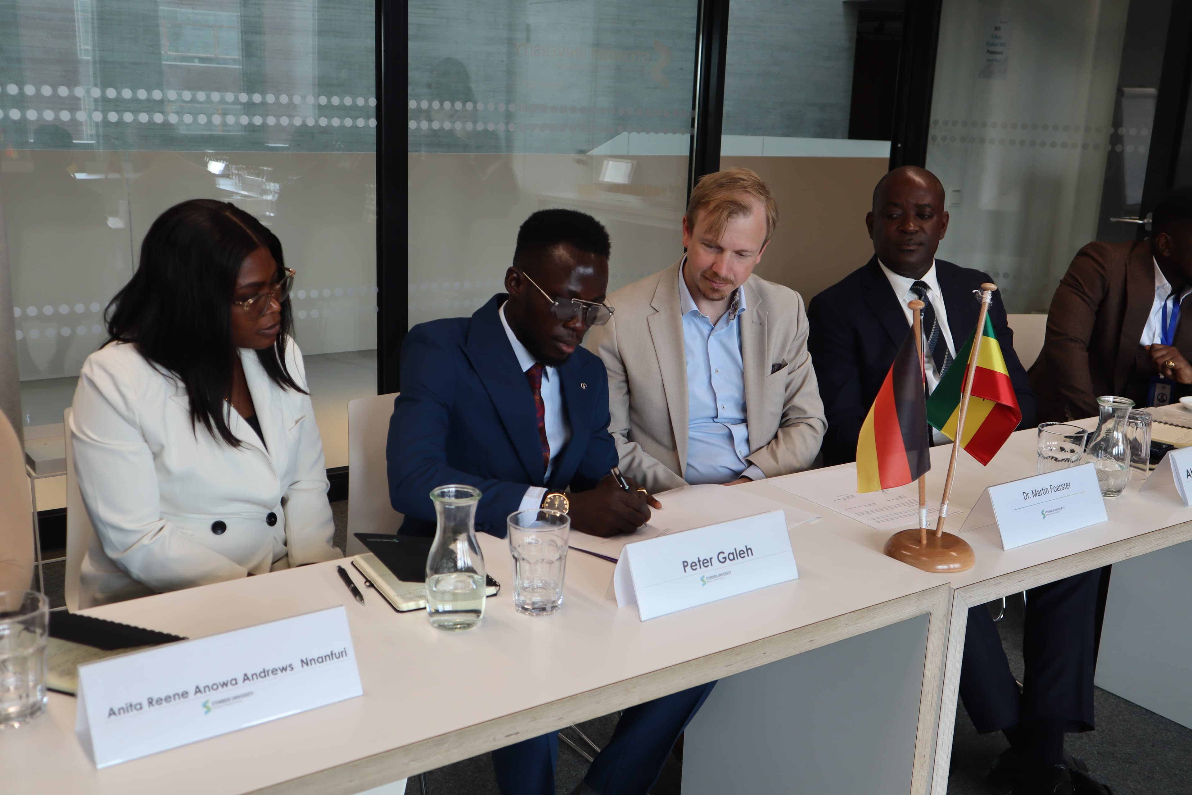 Delegation members seated together beside Ghanaian and German flags.